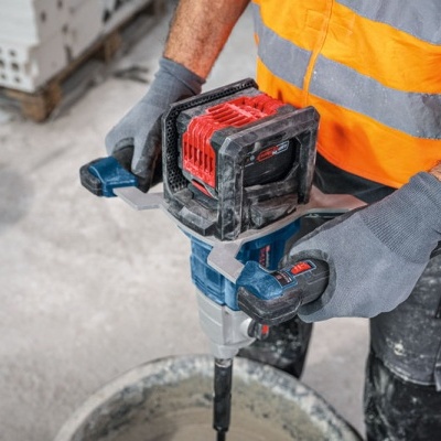 Pessoa com colete refletor e luvas a usar ferramenta elétrica numa construção