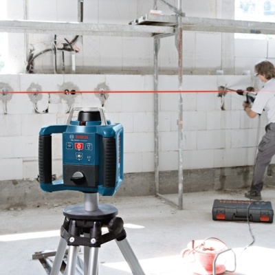 Laser rotativo em tripé a medir um muro branco em ambiente de construção