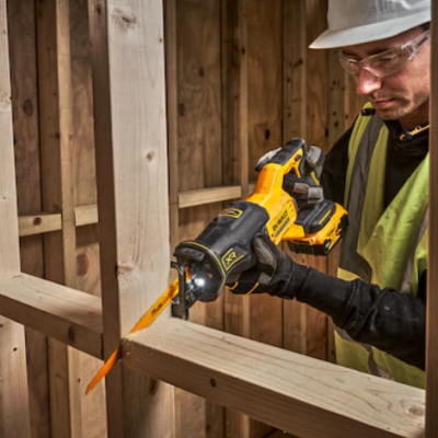 Serra rebarbadora amarela e preta a cortar madeira com operário em equipamento de segurança