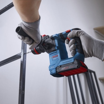 Parafusadora elétrica BOSH Professional azul e preta usada com luvas cinzentas numa estrutura metálica preta