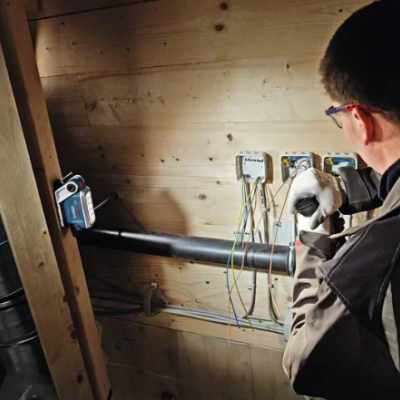 Homem a trabalhar numa instalação elétrica em parede de madeira com tubos e fios