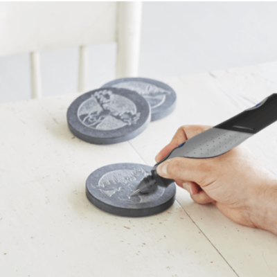 Mão a usar ferramenta elétrica para gravar discos cinzentos sobre uma mesa branca