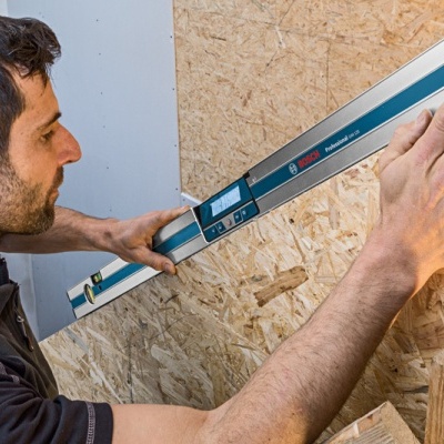 Homem a usar nivelador Bosch Professional numa placa de madeira aglomerada