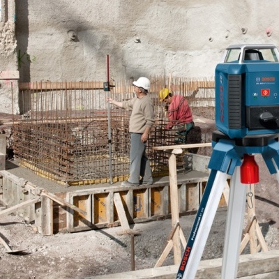 Laser de construção Bosch GLL 3-80 em tripé num canteiro de obras com trabalhadores