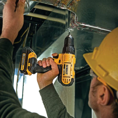 Pessoa a usar furadeira/parafusadora DEWALT preta e amarela em estrutura metálica