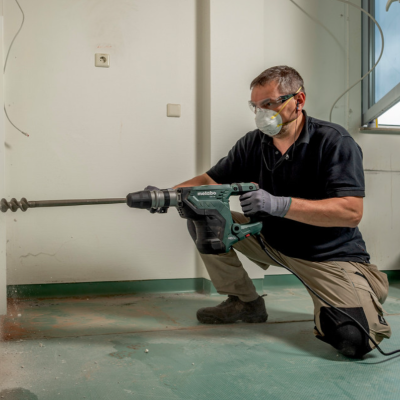 Homem com martelo perfurador elétrico a perfurar uma parede interior