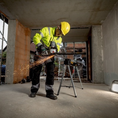Homem a usar corta-ferro com capacete e colete amarelo em obra