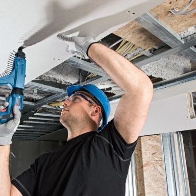 Homem a usar ferramenta elétrica para perfurar teto em obra