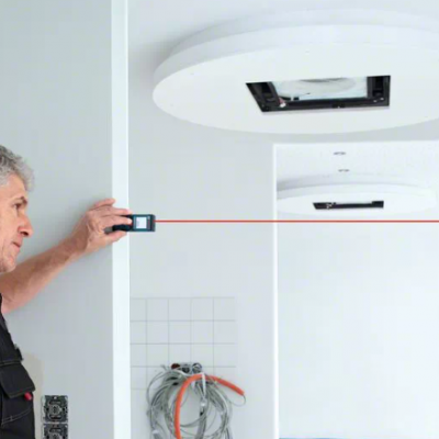 Homem usando aparelho de medição a laser em parede branca