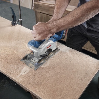 Máquina de serra circular azul cortando madeira clara em oficina