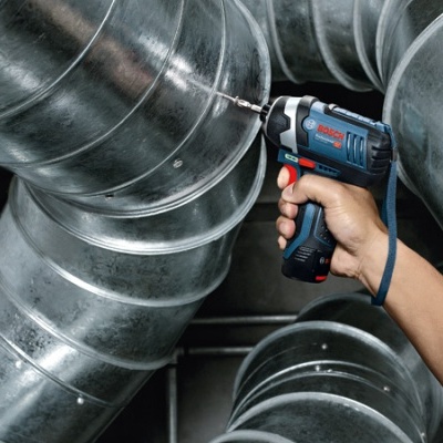 Parafusadeira elétrica a trabalhar em tubo metálico de ventilação