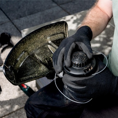 Pessoa a segurar máquina aparadora de relva em ambiente ao ar livre