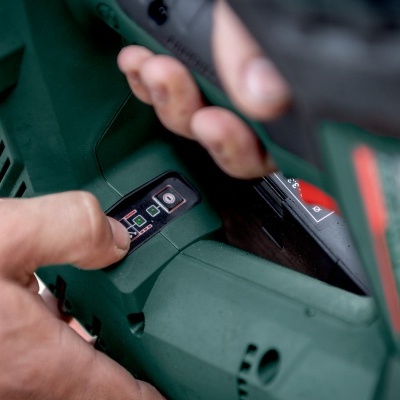 Ferramenta elétrica verde com detalhes vermelhos e texto 18V, em mãos.