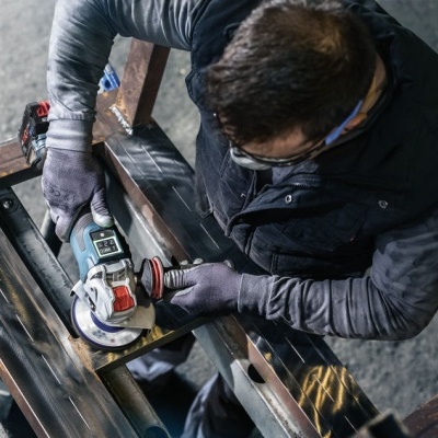 Homem a usar lixadora elétrica para trabalhar metal em oficina