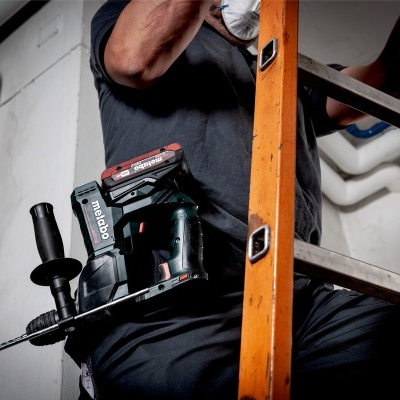 Trabalhador numa escada com furadeira Metabo preta e vermelha presa ao cinto