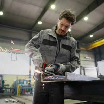 Trabalhador a esmerilhar metal numa oficina industrial