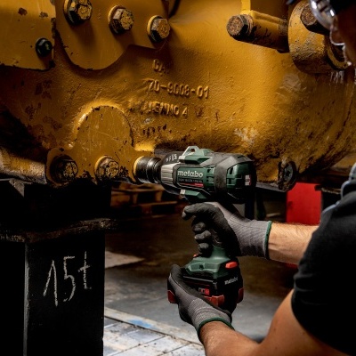 Parafusadeira verde e preta aperta parafuso em equipamento amarelo na oficina