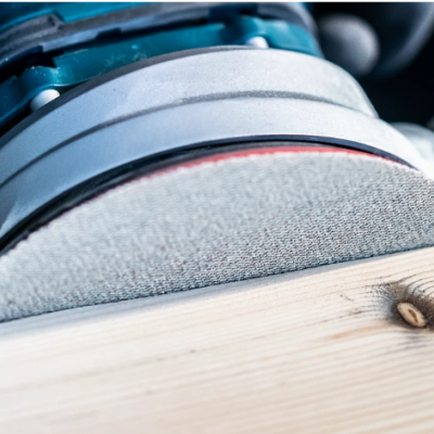 Lixadora eléctrica a lixar uma tábua de madeira clara