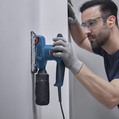 Homem usando ferramenta elétrica para trabalhar em parede