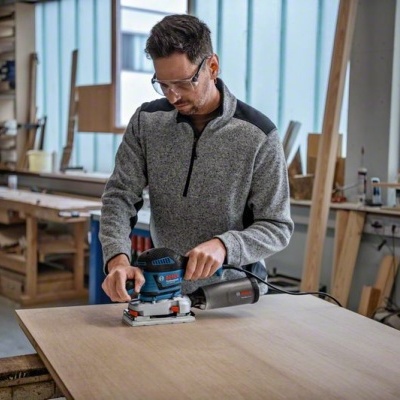 Máquina elétrica de lixamento Bosch em bancada de madeira na oficina.
