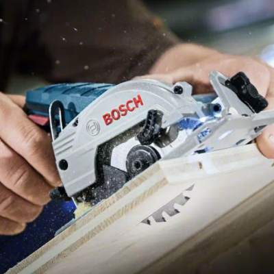Serra circular portátil Bosch azul e cinza a cortar madeira clara