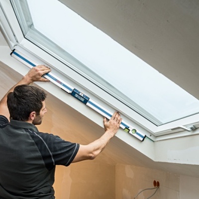 Homem a usar nível de bolha numa janela de teto