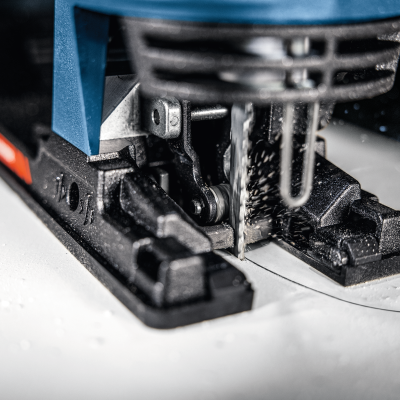 Serra tico-tico elétrica azul e preta a cortar superfície branca