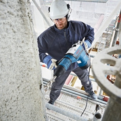 Homem a perfurar betão com máquina em andaime