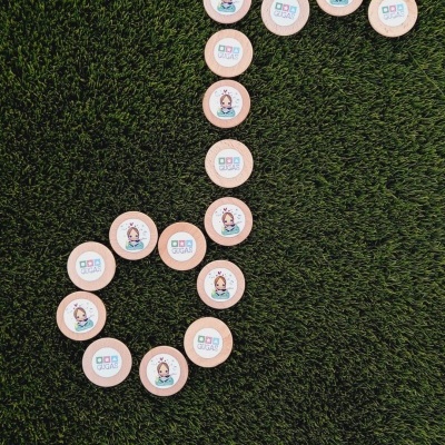 Fichas com logotipo e desenho de personagem em formato de nota musical sobre relva artificial