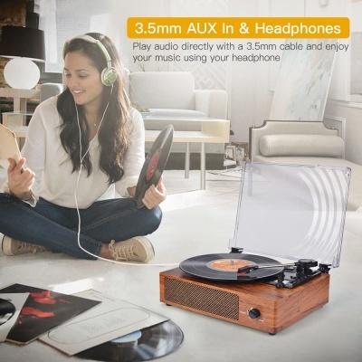 Toca-discos de madeira com tampa transparente e mulher com auscultadores verdes a segurar disco de vinil