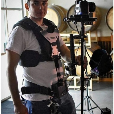 Homem com arnês preto e equipamento de filmagem em espaço interno