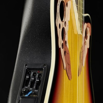 Guitarra acústica com corpo em gradiente vermelho, amarelo e preto com orifícios decorativos e controlo eletrónico