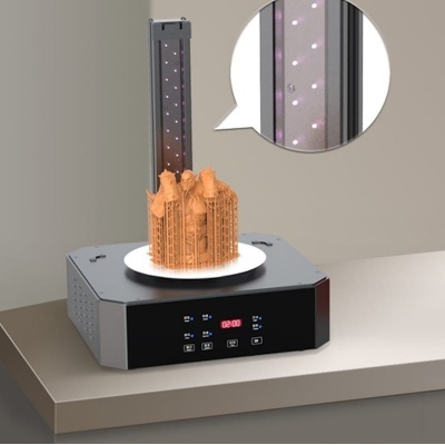 Impressora 3D cinza com modelo laranja sendo impresso