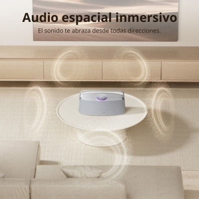 Coluna de som cinzenta sobre mesa branca redonda com texto publicitário ao fundo