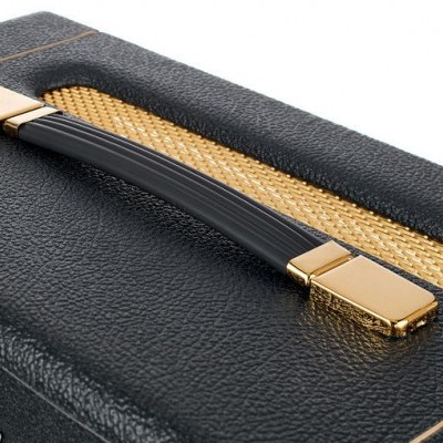 Caixa acústica preta com detalhes dourados e pega preta