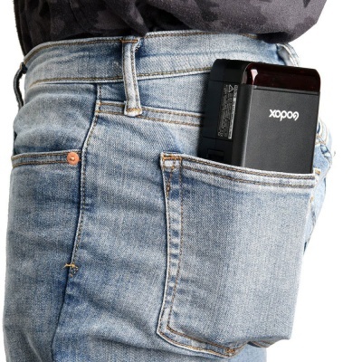 Aparelho preto Godox no bolso de calças de ganga azul claro