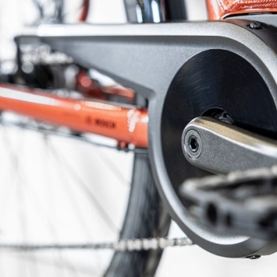 Detalhe de bicicleta laranja com pedais e corrente em foco