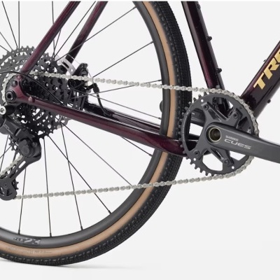 Roda traseira e transmissão de bicicleta bordô TREK com pedaleira SHIMANO EGRESS e pneus com faixa bege.