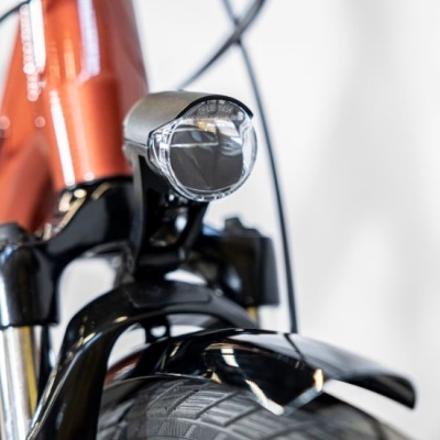 Frente de bicicleta com farol, guarda-lamas preto e quadro laranja