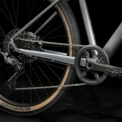 Parte traseira de bicicleta cinza com roda preta e bege e transmissão com corrente e pedaleira