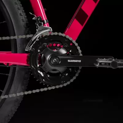 Pedaleira preta Shimano numa bicicleta de quadro rosa com corrente e pneu visíveis