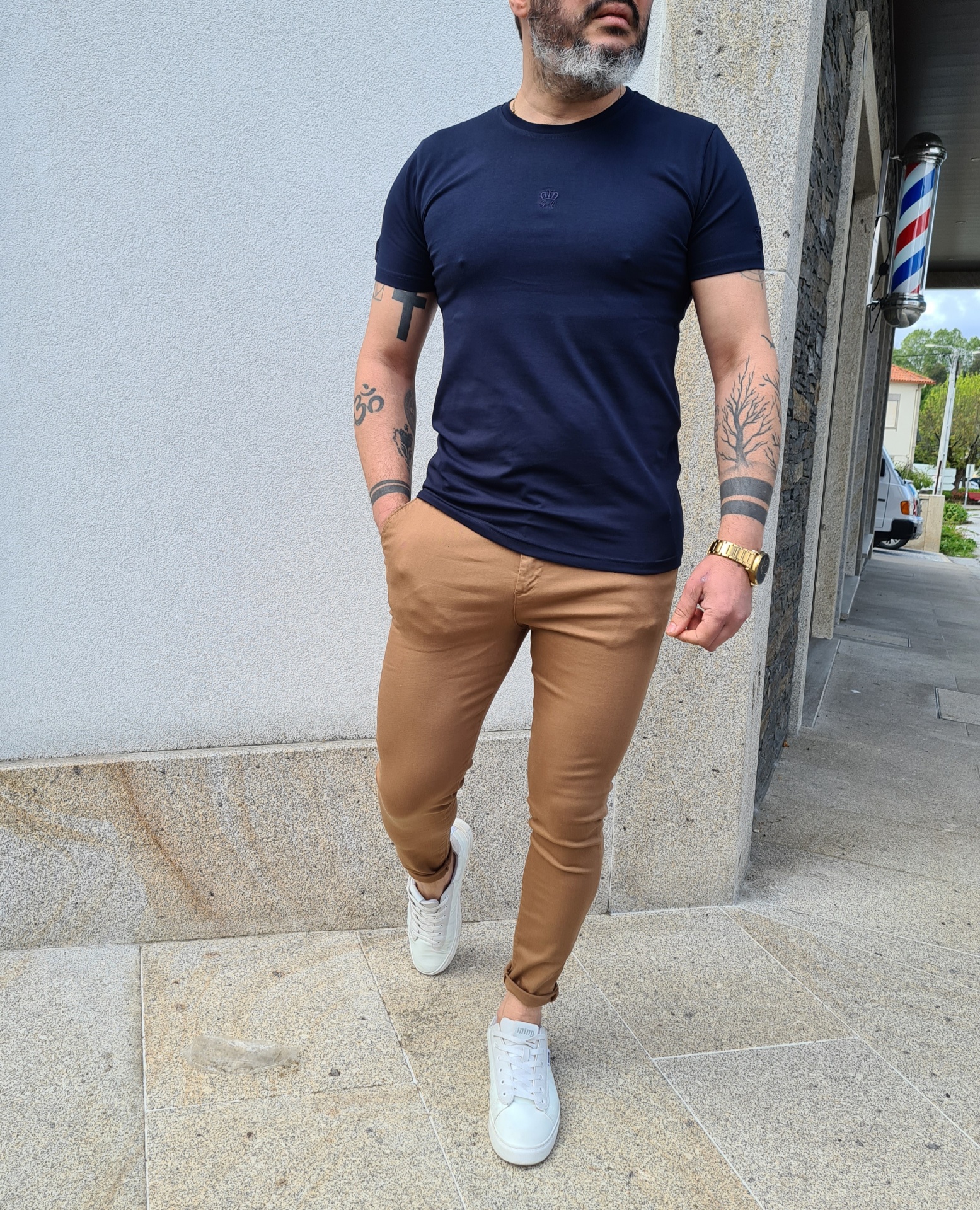 Homem com roupa casual num ambiente exterior perto de uma barbearia