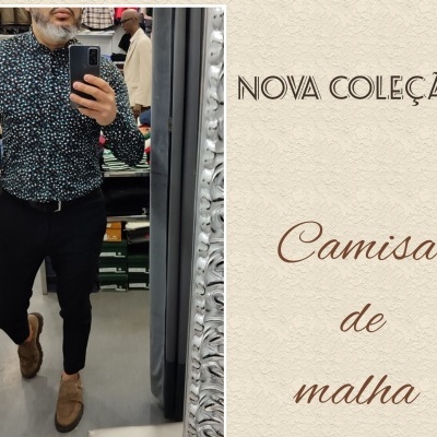Homem com camisa de malha preta com padrão colorido, calças pretas e sapatos castanhos