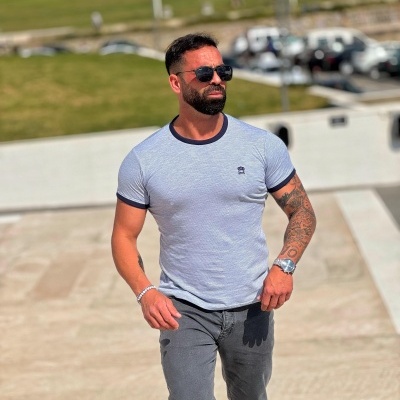 Homem com t-shirt cinzenta e calças cinza escuro ao ar livre