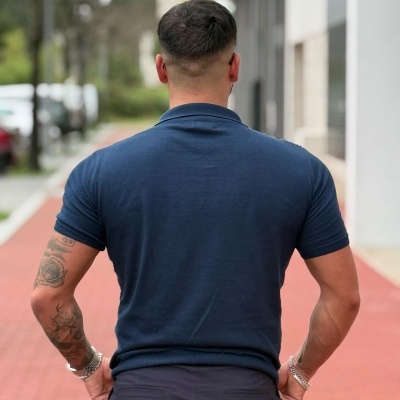 Homem de costas vestindo polo azul escuro de manga curta em ambiente urbano