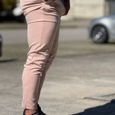 Calças rosa claro justas com ténis pretos e solado branco ao ar livre