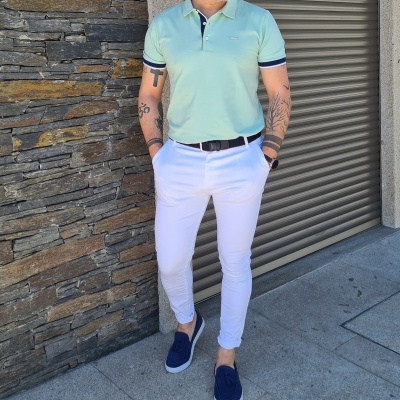 Homem com camisa polo verde claro, calças brancas e sapatos azuis