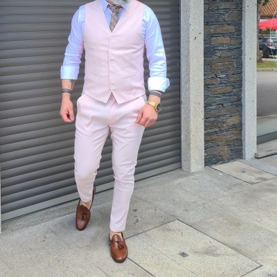 Homem vestido com colete e calças cor de rosa claro e camisa branca