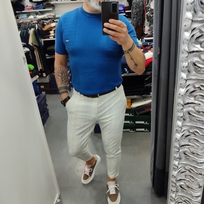 Homem a usar roupa casual azul, branca e castanha a tirar selfie em loja de roupa