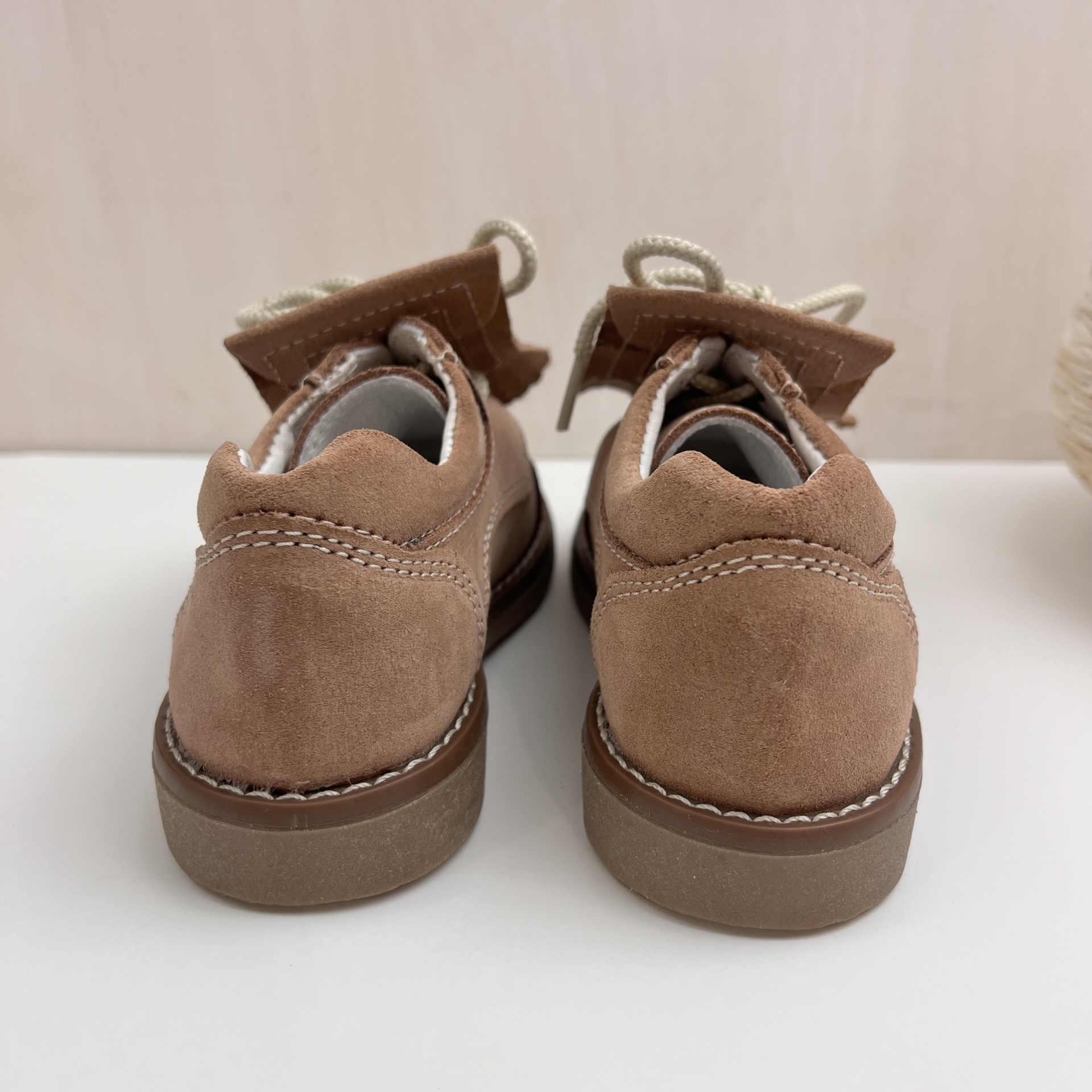 Sapatos de camurça castanha vistos de trás com cadarços brancos